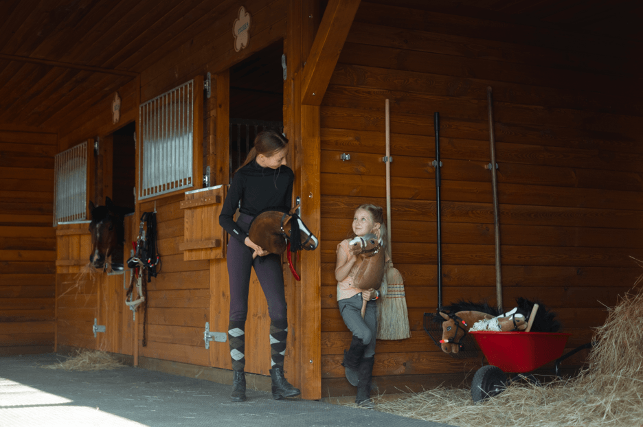 Young people with Hobby Horses outside wooden riding club stables
