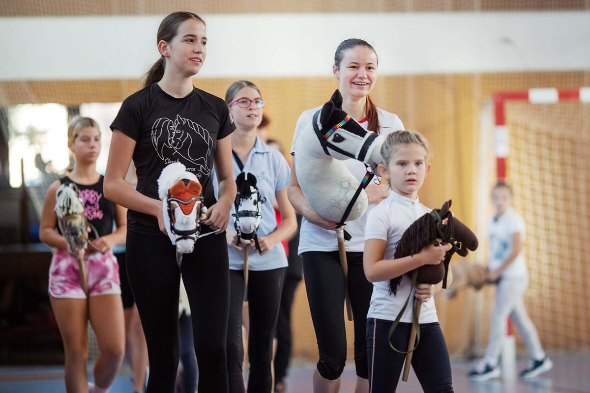 Kinder und Jugendliche halten Hobby Horses bei einem Indoor-Hobby-Horsing-Event