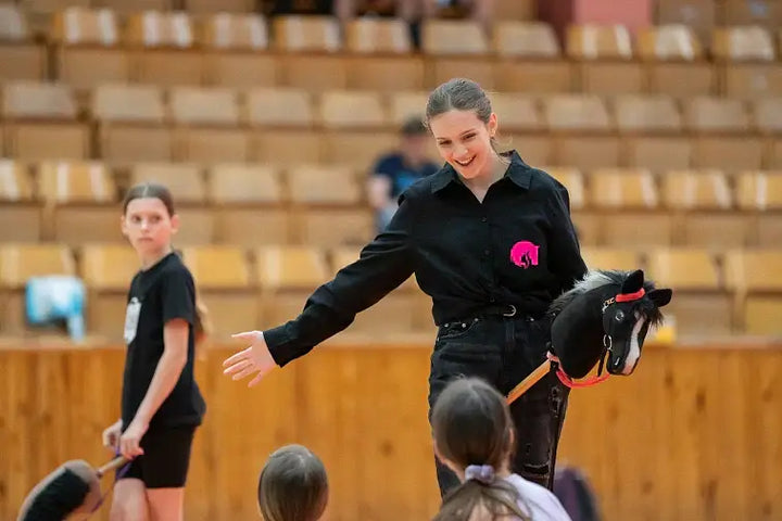 Hobby Horsing demonstration in a sports hall with a woman holding a black Hobby Horse