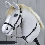 Martingale schwarz von Hobby Horse LarDen auf einem realistischen grauen Hobby Horse Spielzeug mit heller Mähne, weißer Blesse und schwarzem Zaumzeug, an einem Holzstab befestigt vor einem grauen Holzzaun.