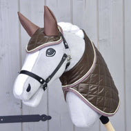 Hobby Horse LarDen Set Thermo Chocolate mit grauem Hobby Horse mit großen Augen, glänzender brauner gesteppter Decke und passender Ohrenkappe, auf einem Stab vor einer hellen Holzwand.