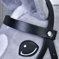 Nahaufnahme des Gesichts eines grauen Plüschspielpferds mit Schwarzes Zaumzeug aus Kunstleder von Hobby Horse LarDen, mit aufgesticktem schwarz-weißem Auge und weichem, strukturiertem Stoff mit sichtbaren Nähten.