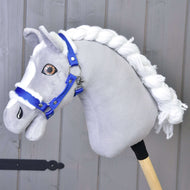 Hobby Horse gris en tissu avec crinière blanche en fil et le licol bleu avec fourrure « Hobby Horse LarDen », devant un mur en bois gris clair.