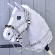 Ensemble de cordes Splendid de Hobby Horse LarDen, Hobby Horse en peluche gris avec crinière blanche, yeux noirs, bride en corde et rênes, présenté devant un mur en bois gris.