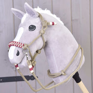 A gray plush hobby horse with a white mane and blaze, wearing the Rope set Eleganza by Hobby Horse LarDen, stands in front of a light wooden wall.