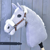 The Hobby Horse LarDen plush gray hobby horse features a white mane and a brown fur-trimmed leatherette halter, mounted on a wooden stick and set against a gray wooden wall.