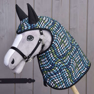 A plush Hobby Horse LarDen with a black halter wears the Raincoat Lara, featuring a blue, green, white, and black houndstooth hood and ears, posed in front of a wooden fence.