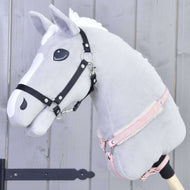 Tour de poitrine avec fourrure de mûrier de Hobby Horse LarDen sur un Hobby Horse gris en peluche avec crinière blanche, bride noire, licol rose et tour de poitrine doux en fourrure, sur un bâton en bois devant un fond en bois gris clair.