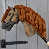 Hobby Horse Lucas mit Schwarzem Halfter - Größe S von Hobby Horse LarDen, ein braunes Hannoveraner-Hobby Horse mit langer Garnmähne, ist mit einer Metallhalterung an einer Holzwand befestigt.