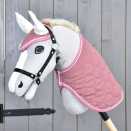 Das Hobby Horse LarDen „Set Dusty Rose“ zeigt ein graues Hobby Horse mit weißer Mähne, schwarzem Zaumzeug, Ohrenkappe, gesteppter rosa Decke und schwarzem Stockgriff, präsentiert vor einer Holzwand.
