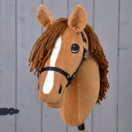 Hobby Horse Wendy mit Schwarzem Halfter von Hobby Horse LarDen zeigt einen braunen Plüschkopf, eine geflochtene braune Garnmähne, einen weißen Streifen an der Schnauze und ein schwarzes Halfter für Hobby Horse, inspiriert von einer Fuchsstute und vor einem grauen Holzhintergrund.