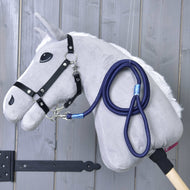 The Hobby Horse LarDen "Hobby Horse - rope stripe Blues" features a plush gray horse with a black bridle and blue leash on a wooden stick, displayed against a gray wooden wall.