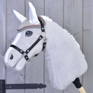 Gros plan sur un Hobby Horse en peluche gris de Hobby Horse LarDen, avec bride, frontal décoratif et Bonnet d'Oreilles Argent Élégance pour la protection contre les insectes, devant une clôture en bois.