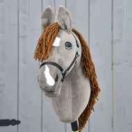 Hobby Horse LarDen Hobby Horse Chanell mit Schwarzem Halfter mit grauem Fell, brauner Garnmähne, weißen Gesichtsabzeichen, großen ausdrucksstarken Augen, präsentiert vor einem grauen Holzbackground.