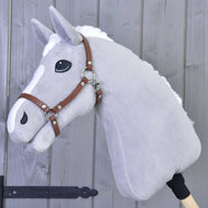 Halfter - braunes Kunstleder von Hobby Horse LarDen an einem grauen Plüsch-Hobby Horse mit weißer Mähne und weißen Abzeichen an der Nase, auf einem Holzstab montiert und vor einer grauen Holzwand gezeigt.