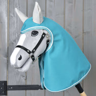 Imperméable turquoise de Hobby Horse LarDen avec Hobby Horse gris, bride noire et capuche style imperméable turquoise, avec visage de forme réaliste aux détails noirs et blancs, sur fond en bois clair.
