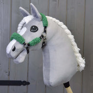 Schwarzes Halfter mit Full Grünem Fell - Kunstleder von Hobby Horse LarDen an einem grauen Plüsch-Hobby Horse, vor einem Hintergrund aus Holzpaneelen gezeigt.