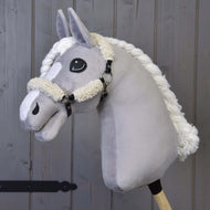 Hobby Horse LarDen mit einem grauen Plüsch-Hobby Horse mit Schwarzes Halfter Full Fell- Kunstleder und Kunstlederakzenten, auf einem Holzstab vor einem Hintergrund aus Holzplanken.
