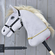 A gray Hobby Horse LarDen with a black bridle, golden mane, and handmade Cordeo Nature hangs on a wooden stick against a gray wall. A yellow polypropylene rope is looped around its neck.