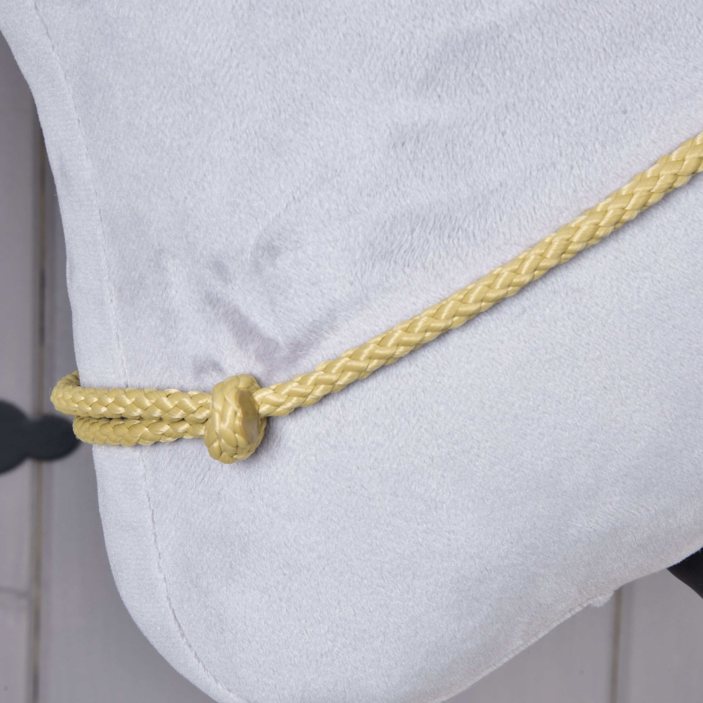 Gros plan sur le Cordéo Nature de Hobby Horse LarDen, montrant un tissu doux gris clair avec un cordon tressé jaune fait main noué simplement le long du bord.