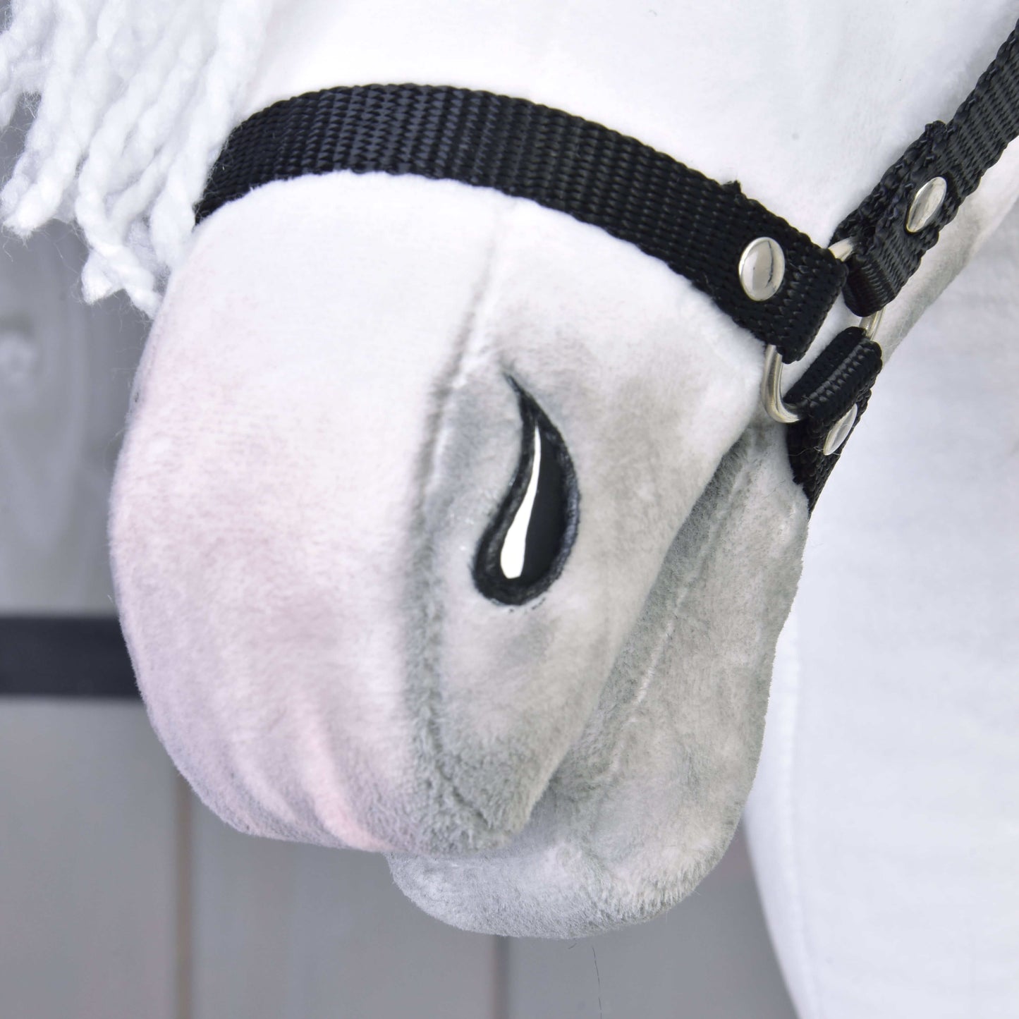 Gros plan sur Hobby Horse Elektra avec licol noir de Hobby Horse LarDen, avec visage blanc en peluche, licol noir, détail noir brodé en forme de larme, texture douce, crinière blanche en fil et traits inspirés d’une jument lipizzane.