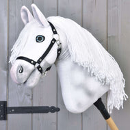 Hobby Horse Elektra mit Schwarzem Halfter von Hobby Horse LarDen mit handbemaltem weißem Kopf, schwarzem Halfter und langer weißer Garnmähne, auf einem Holzstab montiert, vor einer hellgrauen Holzwand.