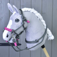 Ein plüschiges grauweißes Hobby Horse mit geflochtener Mähne und schwarzen Augen präsentiert das Hobby Horse LarDen Seilset Grau (Gr. M) vor einer Holzvertäfelung und hebt das einzigartige handgefertigte Reitzubehör hervor.