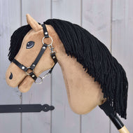 Hobby Horse Samantha mit Schwarzem Halfter von Hobby Horse LarDen mit beigefarbenem Gesicht, schwarzer Garnmähne, gestickten Details und schwarzem Halfter, präsentiert auf hellem Holzuntergrund.