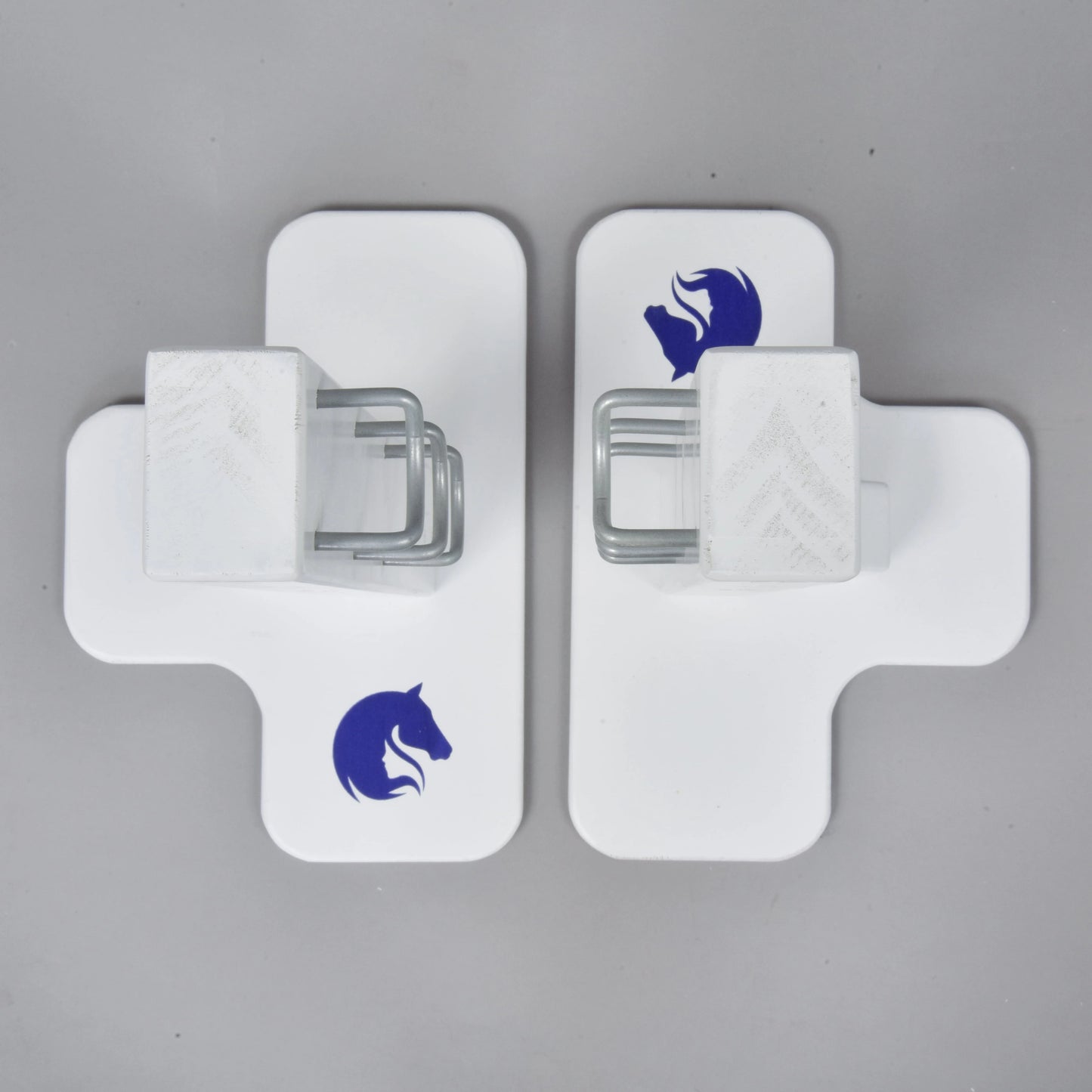 Deux obstacles Jump 50 cm / 20 inch blancs en forme de croix de Hobby Horse LarDen, chacun avec un logo de tête de cheval bleu et un support métallique central, face à face sur une surface grise, idéal comme obstacle de Hobby Horsing à hauteur réglable en intérieur ou en extérieur.