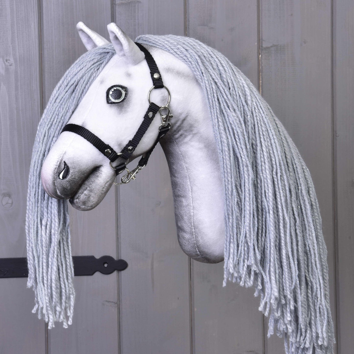 Hobby Horse Einhorn Silver mit Trense und Halfter von Hobby Horse LarDen mit handgefertigtem weißem Stoffkopf, schwarzer Trense und hellgrauer Garnmähne vor grauem Holz-Hintergrund.