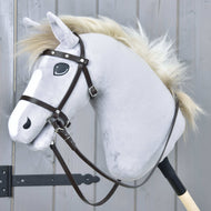 A light gray hobby horse with a white mane and a complete brown bridle with diamonds from leatherette by Hobby Horse LarDen is mounted on a wooden stick in front of a gray wooden door.