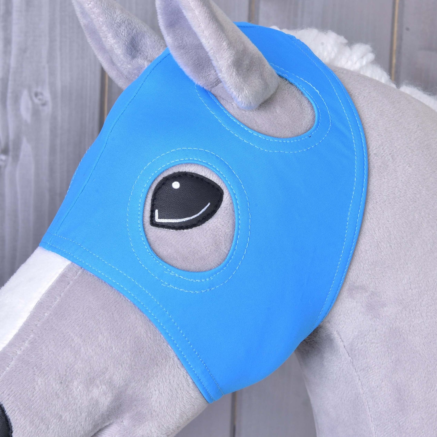 Nahaufnahme eines grauen Spielzeugpferds mit der Hobby Horse LarDen Maske ohne Ohren Sky mit Öffnungen für die Augen vor Holzhintergrund.