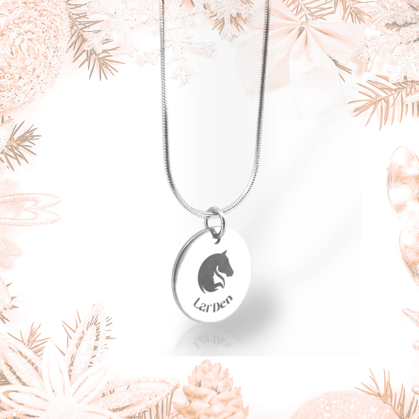 Eine Halskette mit LarDen-Medaillon aus chirurgischem Edelstahl von Hobby Horse LarDen mit rundem Anhänger mit Pferdekopf und dem Wort „Leiden“, gefertigt aus chirurgischem Edelstahl, gezeigt vor weichen rosa-weißen festlichen Dekorationen.