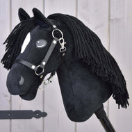 Hobby Horse Cloony mit Schwarzem Halfter von Hobby Horse LarDen, schwarzes Plüsch-Hobby Horse nach dem Vorbild eines American Quarter Horse Hengstes, mit weißem Fleck nahe dem Auge, schwarzer Garnmähne und schwarzem Halfter, auf hellem Holzuntergrund.