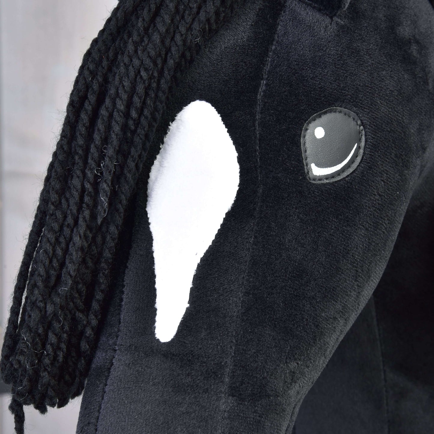 Gros plan sur Hobby Horse Cloony avec licol noir de Hobby Horse LarDen, Hobby Horse noir en peluche avec tache blanche sur le visage, crinière noire en fil et œil brodé avec reflet blanc.