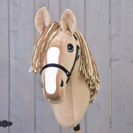 Hobby Horse Bren mit Schwarzem Halfter von Hobby Horse LarDen mit hellbraunem Plüschkörper, weißer Blesse und creme-brauner Garnmähne vor hellem Holz-Hintergrund.