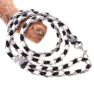 The Hobby Horse LarDen Braided lead rope in black and white, inspired by classic horse gear, features a durable metal clasp and is shown coiled on wood.