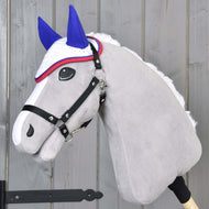 The Hobby Horse LarDen gray plush hobby horse features a black bridle and the Moody crocheted blue and white ear bonnet with a red-edged crownpiece, shown against a light wooden background.