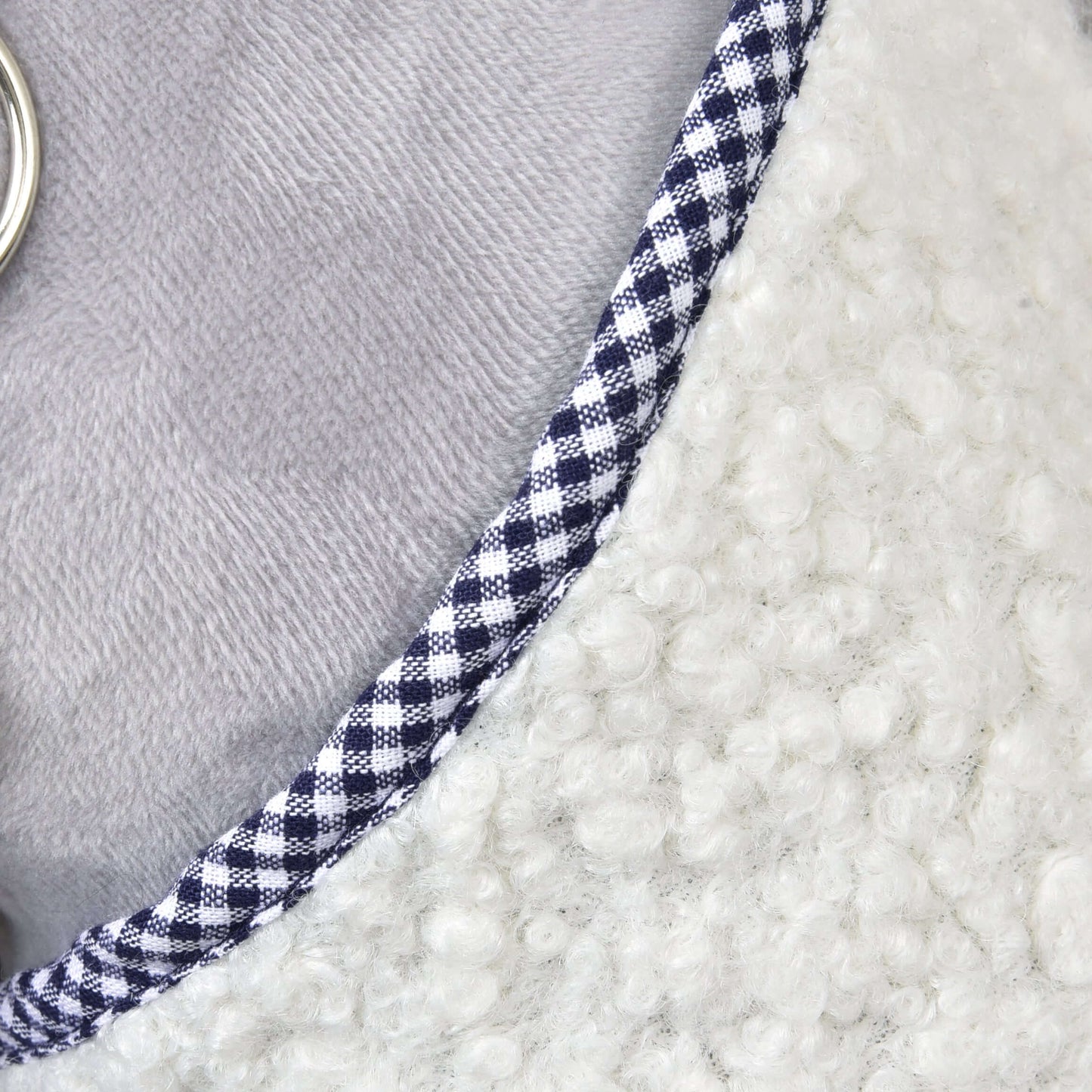Nahaufnahme von Decke Cube Blue von Hobby Horse LarDen mit Fokus auf das strukturierte weiße Fleece, den blau-weiß karierten Besatz, den glatten hellgrauen Stoff und einen kleinen silberfarbenen Ring am linken Rand.