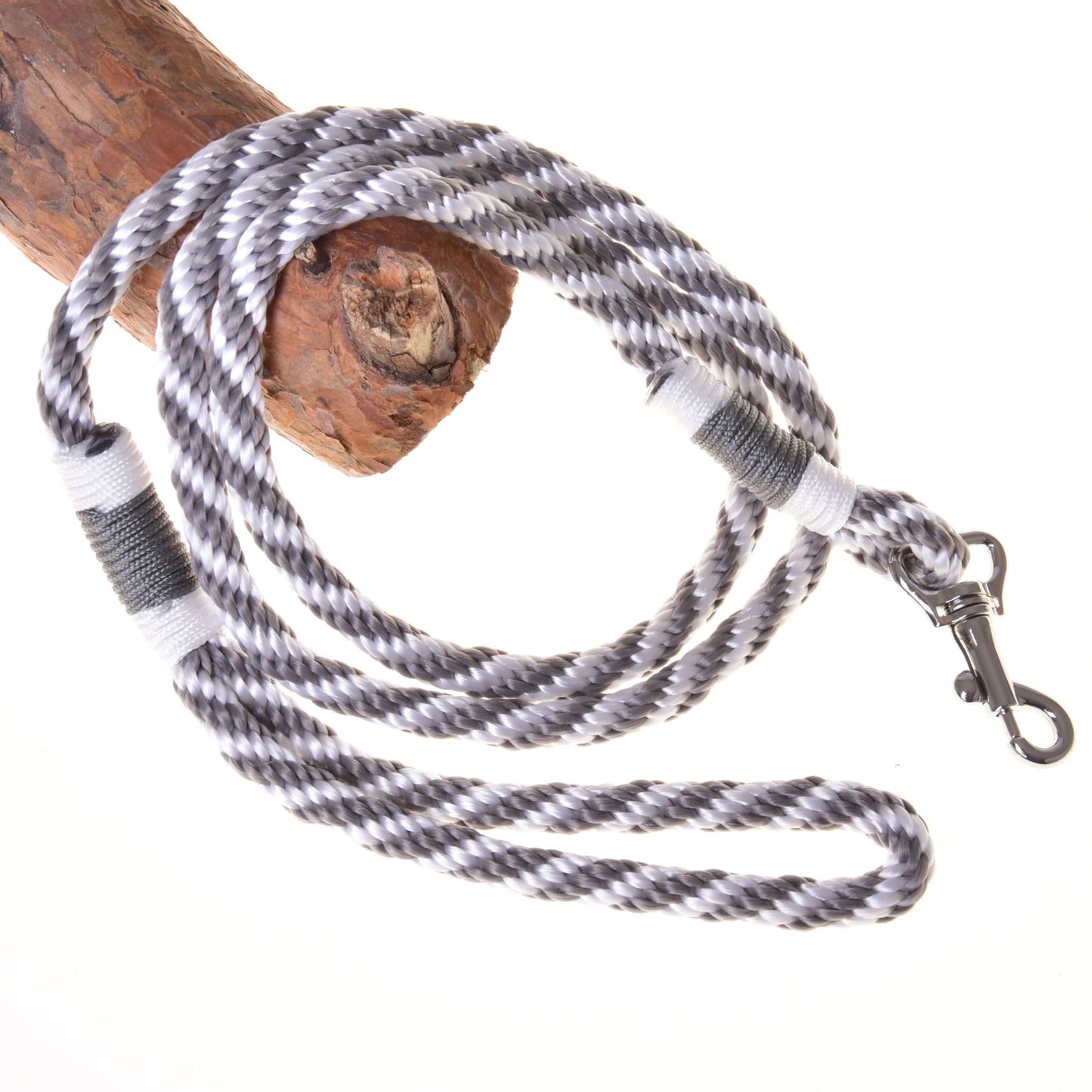 Set Start Silber (Halfter + Halsring + Führstrick + Zügel) von Hobby Horse LarDen mit schwarz-weiß-grau gewickeltem Führstrick mit Metallclip, um strukturiertes Holz gewickelt vor weißem Hintergrund gezeigt.