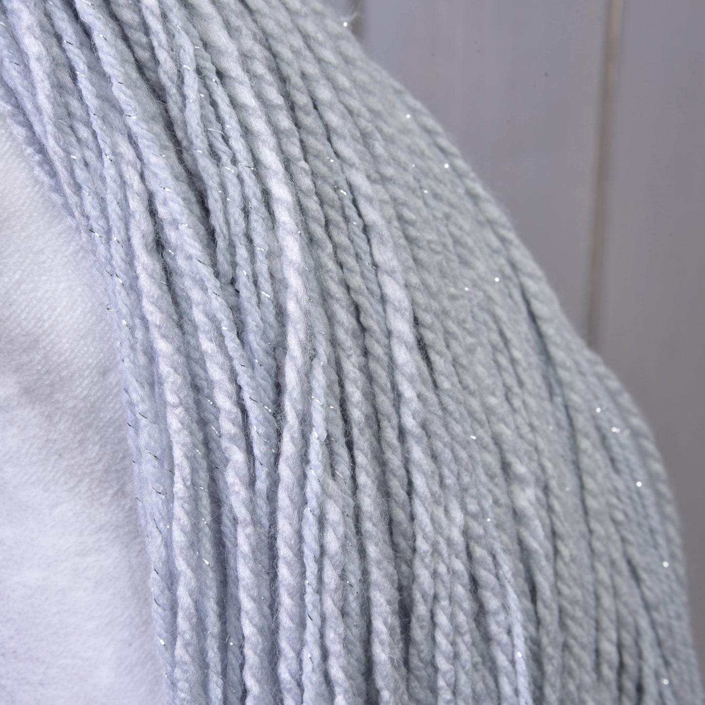Nahaufnahme von Hobby Horse Einhorn Silver mit Trense und Halfter von Hobby Horse LarDen mit blassgrauem Garn mit dezentem silbernem Glitzer, über eine weiße Oberfläche gelegt für einen magischen, vom Einhorn inspirierten Schimmer.