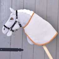 A gray Hobby Horse LarDen with a white mane, black bridle, and a Blanket english brown plaid double-sided is mounted on a wooden stick in front of a gray wooden wall.