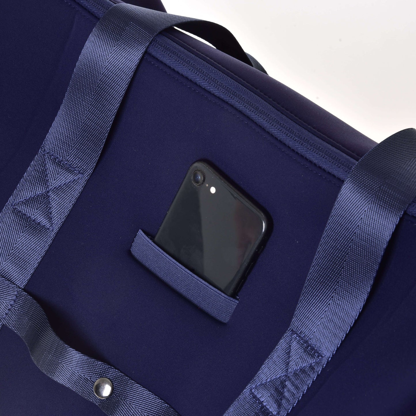 Smartphone noir dépassant d’une petite poche extérieure du Sac de sport LarDen bleu foncé de Hobby Horse LarDen, avec poignées assorties, sangle réglable et format spacieux, idéal pour un usage quotidien.