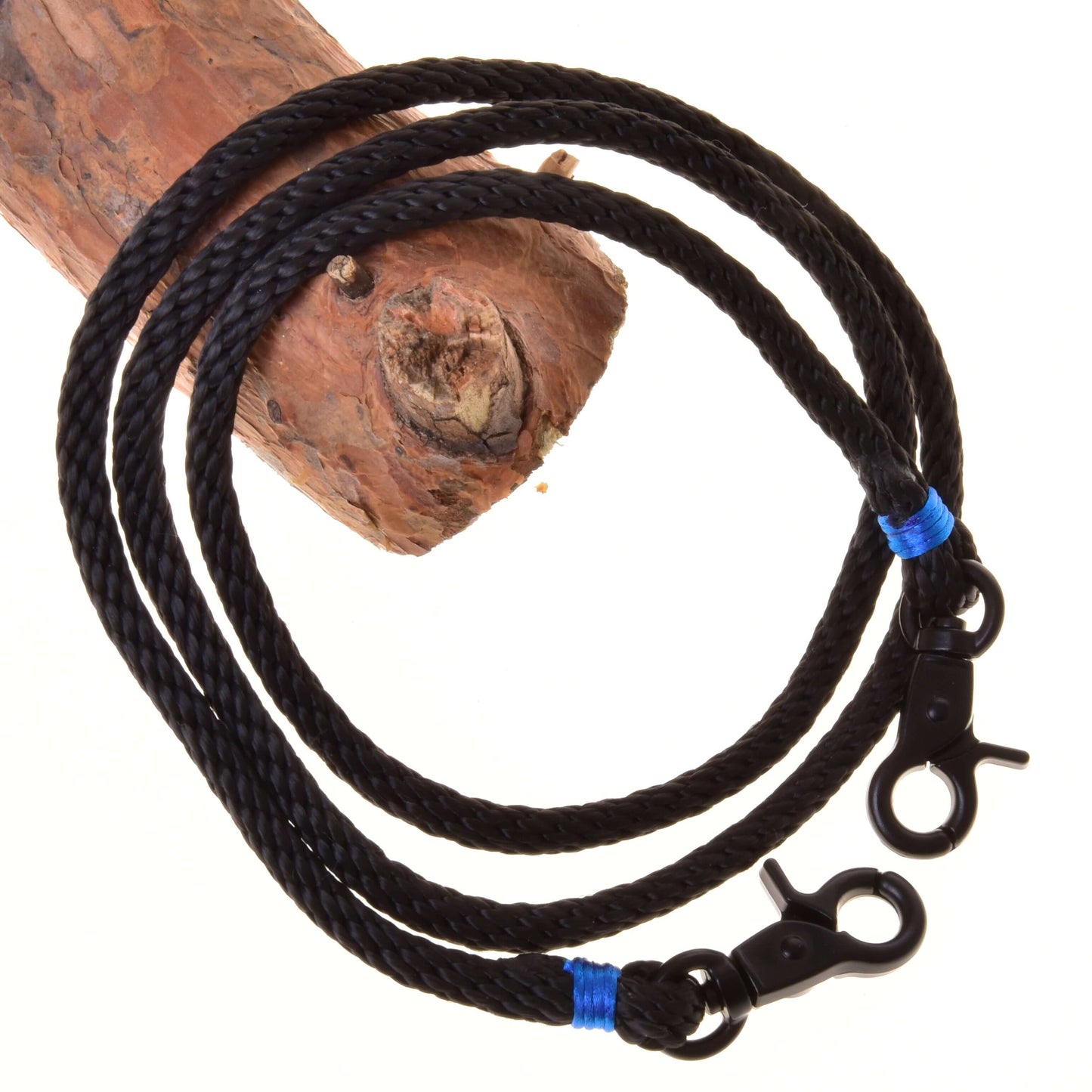 The Reins Azure by Hobby Horse LarDen are black braided polypropylene reins with metal snap hooks and blue bindings, shown draped over wood—ideal handmade reins for your hobby horse.