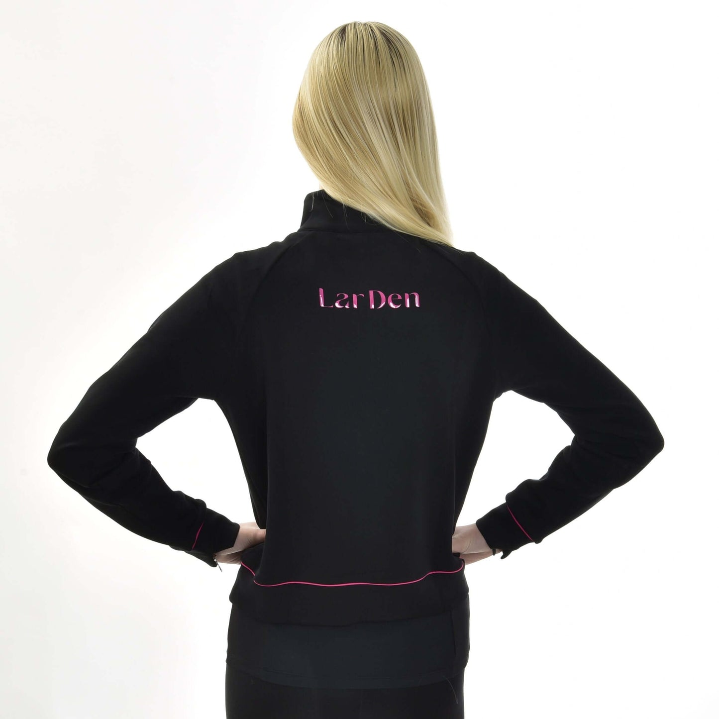 Personne aux longs cheveux blonds lisses vue de dos, portant un sweat-shirt LarDen noir de Hobby Horse LarDen avec lettrage rose au dos et bordures roses aux poignets et à l’ourlet.