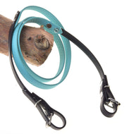 Rênes caoutchoutées turquoise de Hobby Horse LarDen, avec poignée turquoise texturée et accents noirs, passées en boucle sur du bois et présentées sur fond blanc, ressemblant à des rênes élégantes.