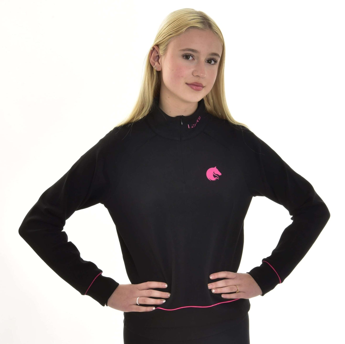 Jeune personne aux longs cheveux blonds debout avec assurance, mains sur les hanches, portant un sweat-shirt LarDen noir de Hobby Horse LarDen avec bordures roses et logo cheval rose, sur fond blanc.