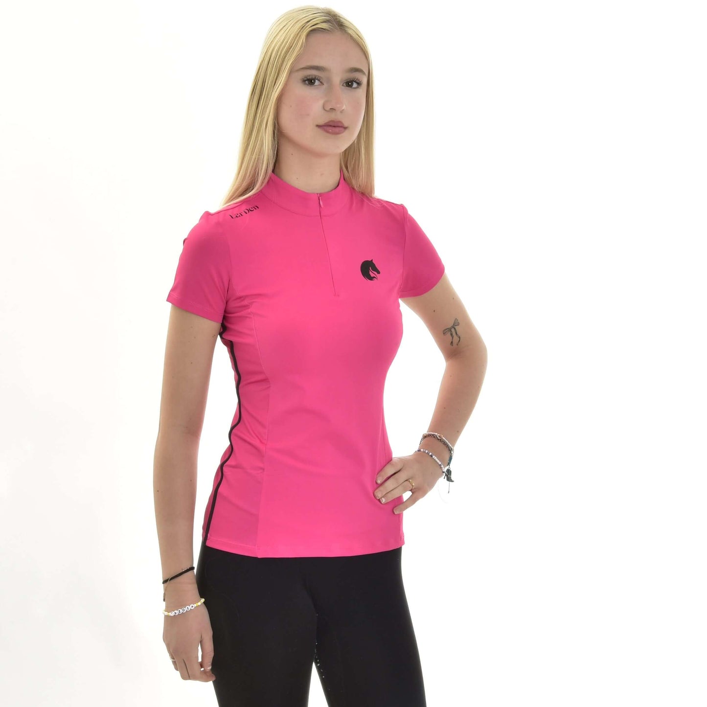 Eine junge Frau mit langen blonden Haaren präsentiert das T-Shirt LarDen Pink von Hobby Horse LarDen, ein leuchtend pinkes Kurzarm-Sportoberteil aus Spandex, kombiniert mit schwarzer Hose und posierend vor schlichtem weißem Hintergrund mit einer Hand in der Hüfte.