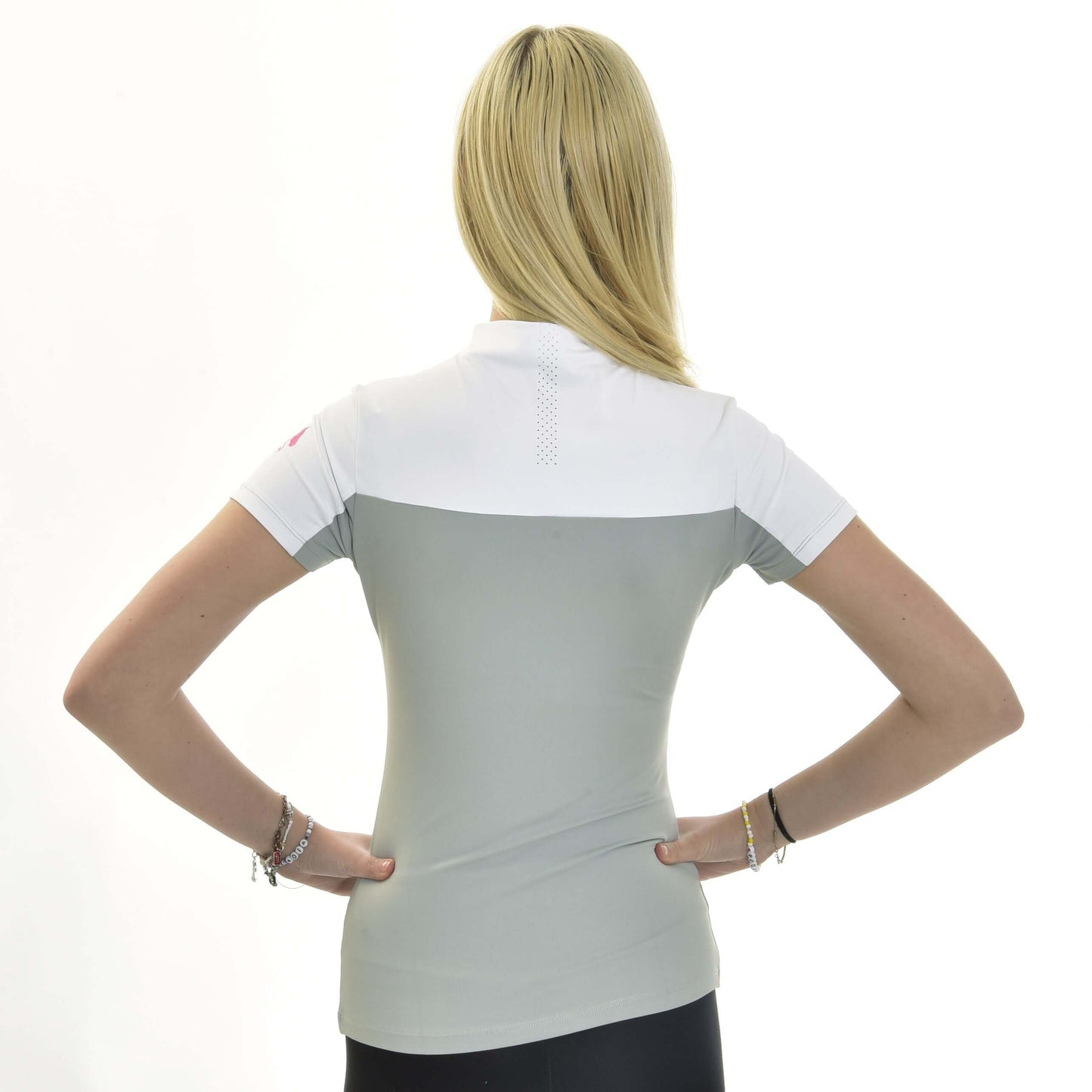 Une femme aux longs cheveux blonds se tient dos à l’appareil, les mains sur les hanches, portant le T-shirt LarDen Premium de Hobby Horse LarDen en spandex blanc et gris clair. Le fond est blanc uni.