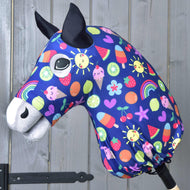 Tête de Hobby Horse en tissu avec oreilles noires, grands yeux et combinaison de protection Hobby Horse Bonheur de Hobby Horse LarDen bleue avec soleils, arcs-en-ciel, cœurs, fruits et glaces, sur fond en bois.